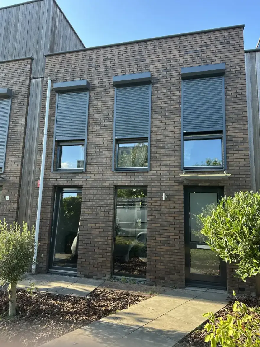 Nieuwbouw rijwoning met drie antraciet rolluiken op de verdieping