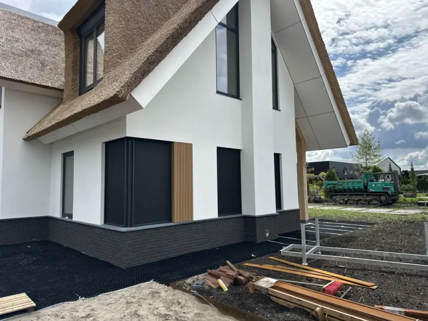 Rietgedekte nieuwbouwwoning met donkere screens voor de ramen