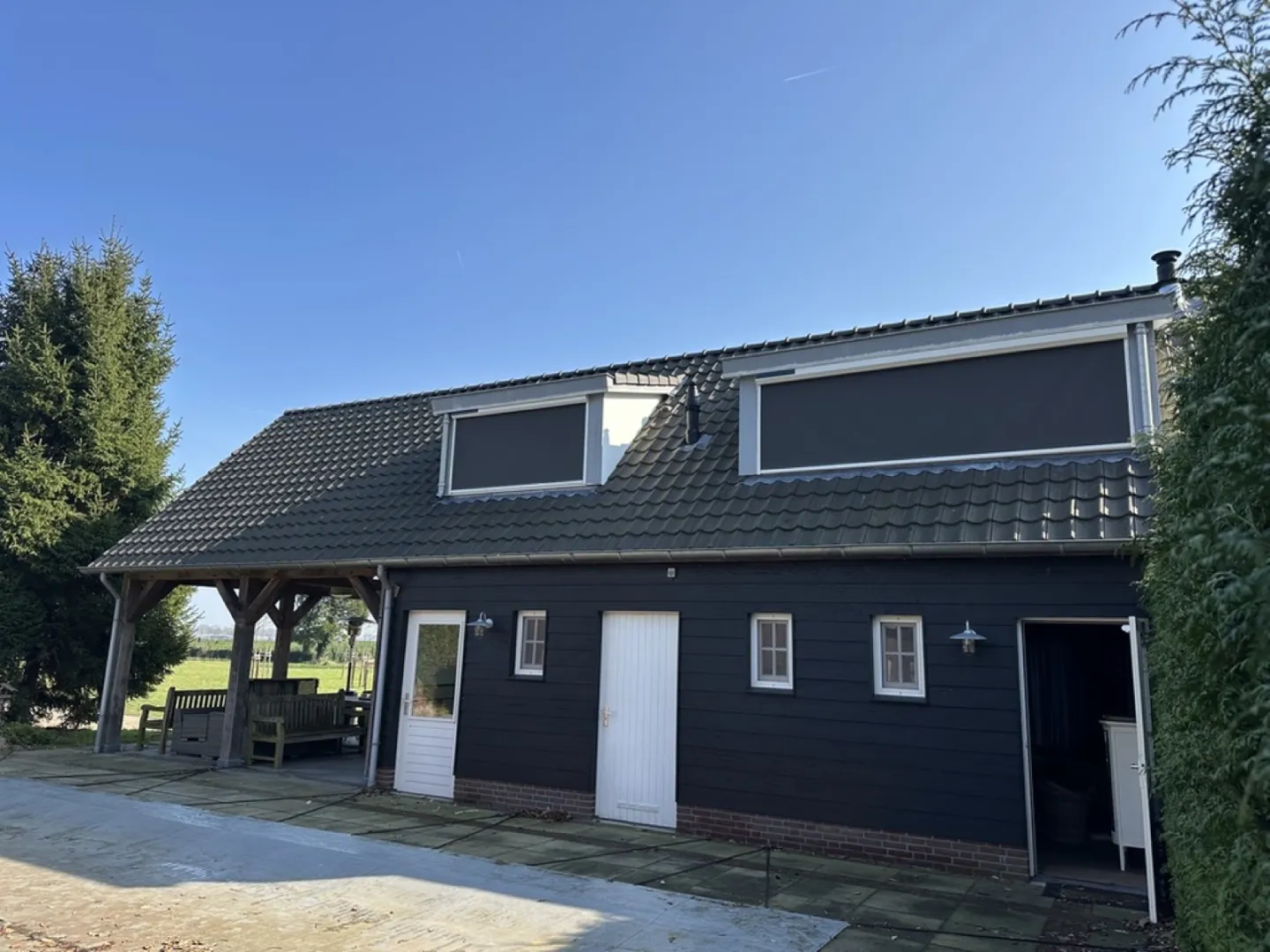 Boerderij met zwarte gevel en screens voor de dakkapellen