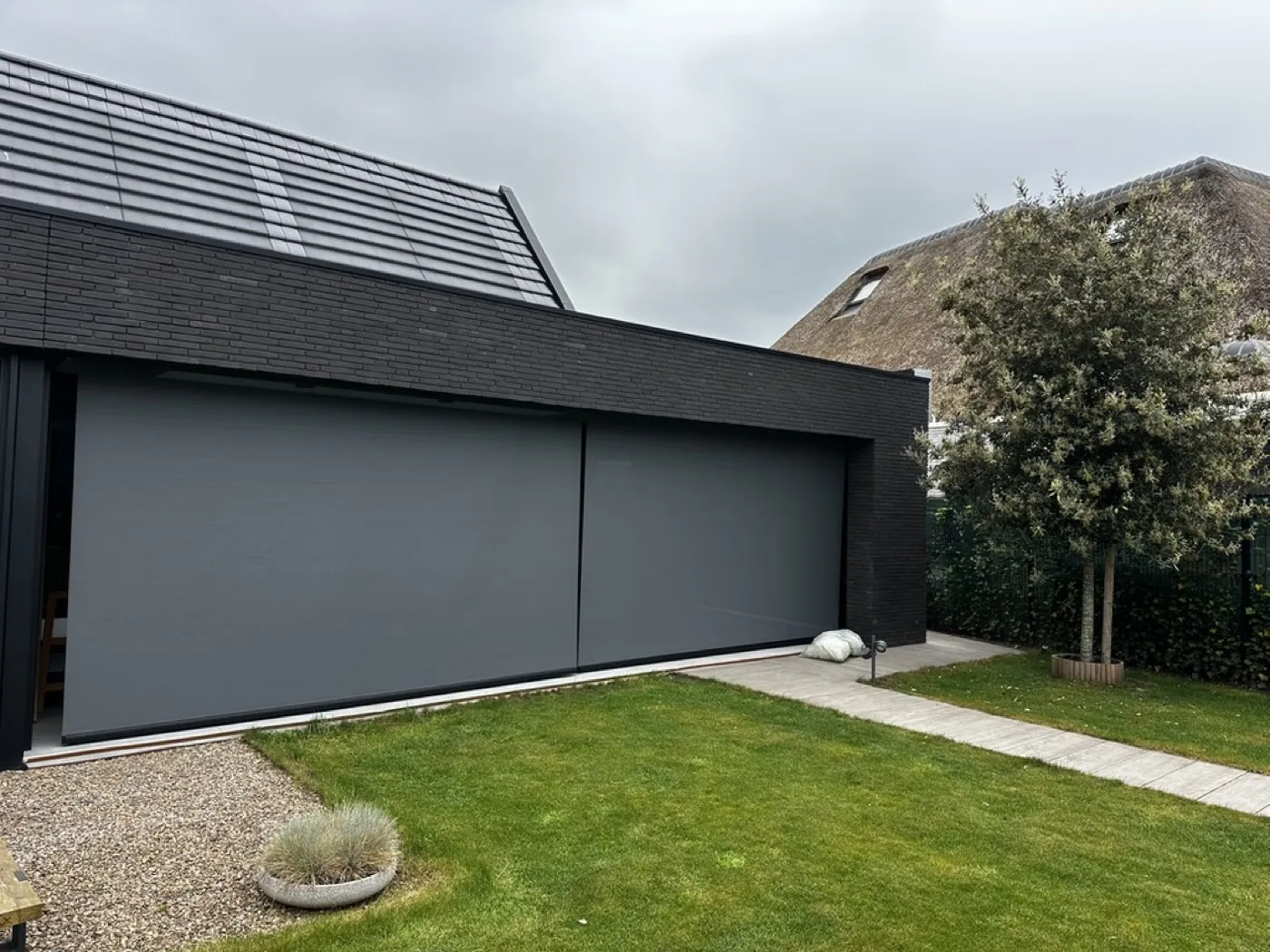 Modern zwart woonhuis met een groot screen op de zijgevel, gemonteerd door Sunvio