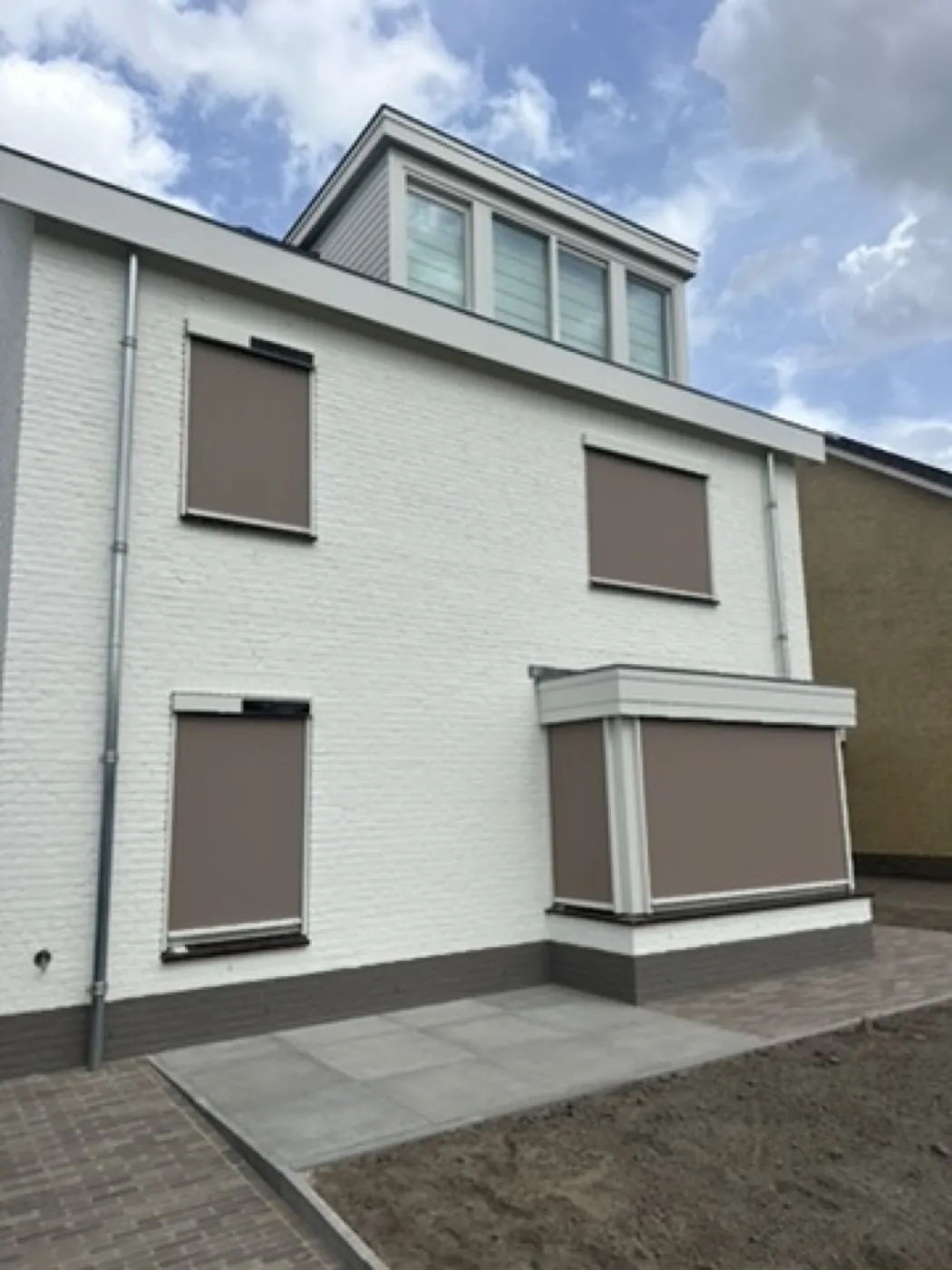 Witte nieuwbouwwoning met taupe screens, gemonteerd door Sunvio