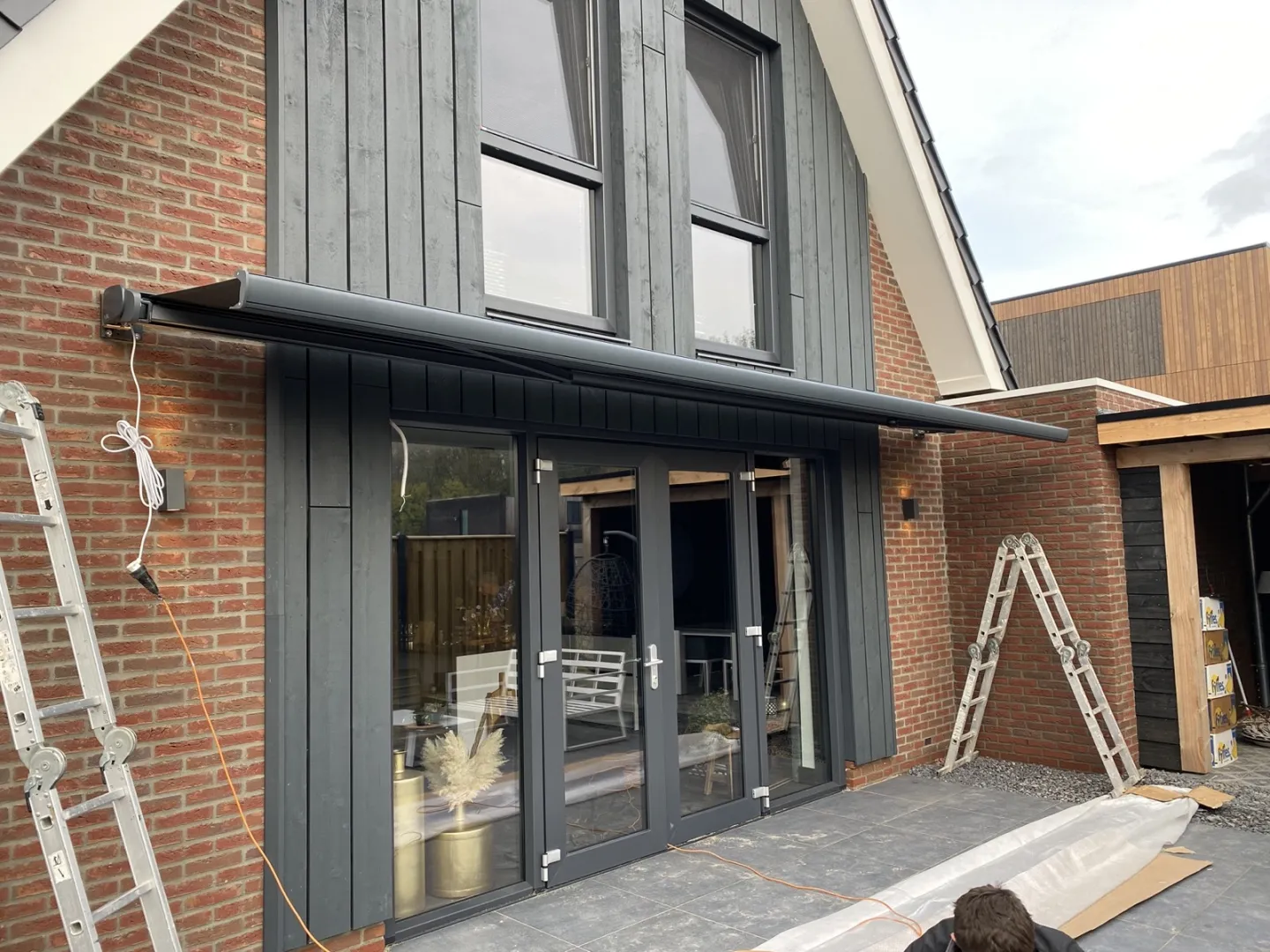 Zonnescherm wordt gemonteerd aan de gevel van een modern huis