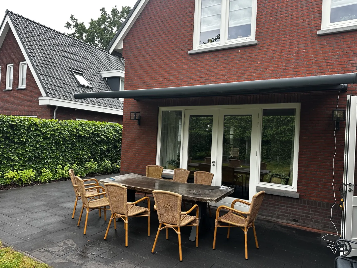 Zonnescherm uitgeschoven over een terras met tuinset